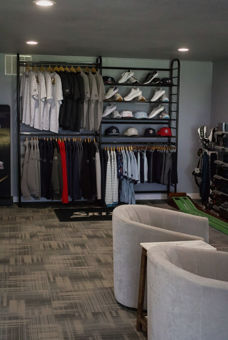 Store display featuring neatly arranged clothing, shoes, and caps on shelves.